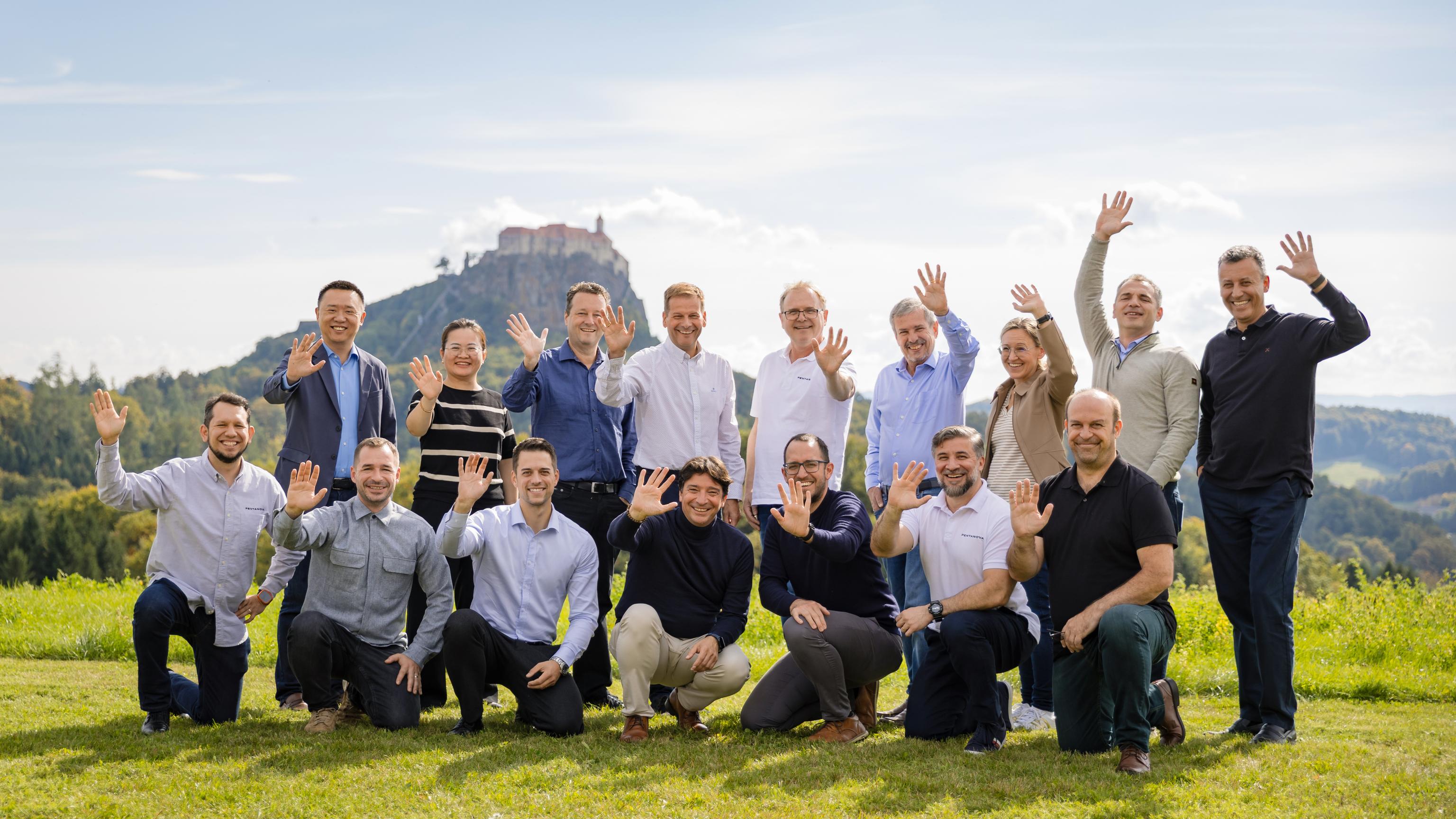 Gruppenfoto auf einer Wiese mit Bergen und einer alten Burg im Hintergrund.