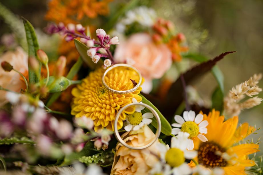 Zwei Ringe liegen auf einem Bündel Blumen.